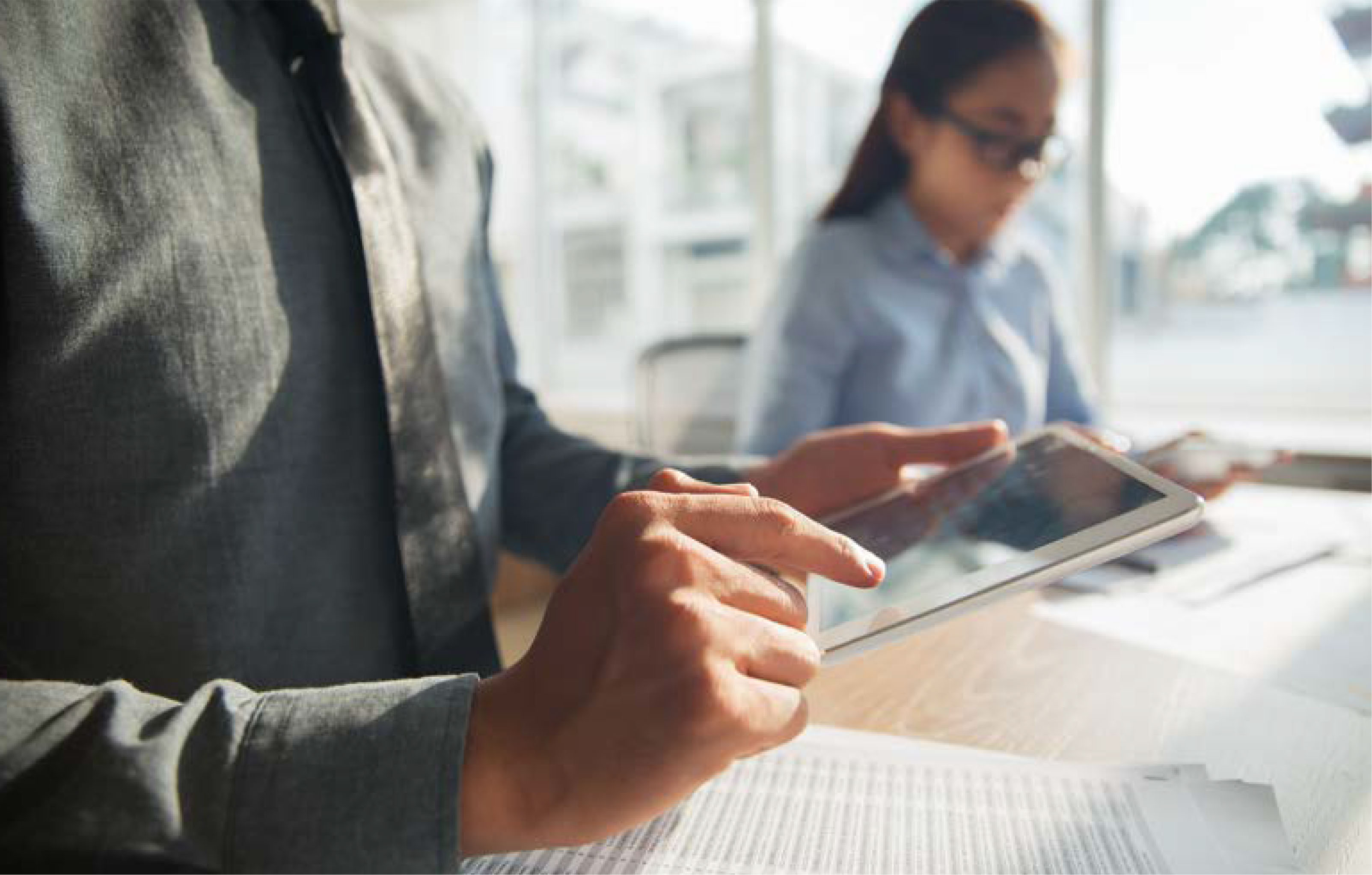 Ejecutivo revisando tablet sobre documentos financieros en oficina, representando empresas que buscan financiamiento para operar