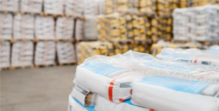Sacos blancos de fertilizante apilados en centro de almacenamiento agrícola