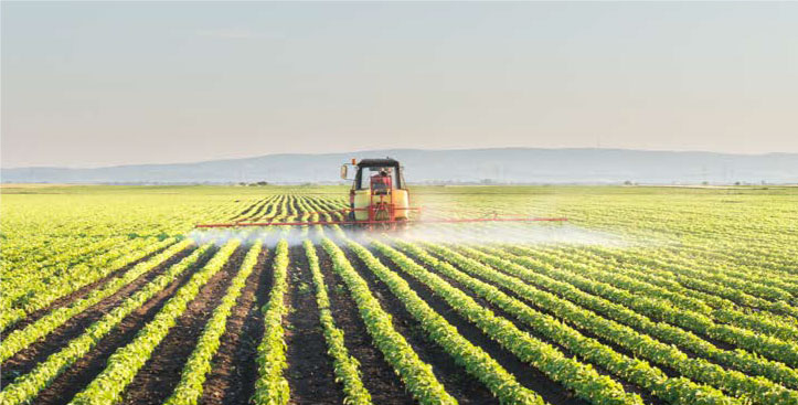 Tractor aplicando agroinsumos en cultivo agrícola representando el uso productivo de garantías