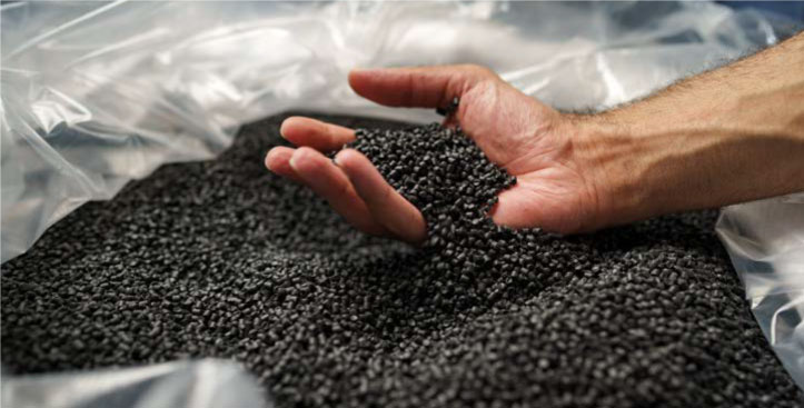 Mano tomando gránulos plásticos negros como materia prima utilizada como garantía